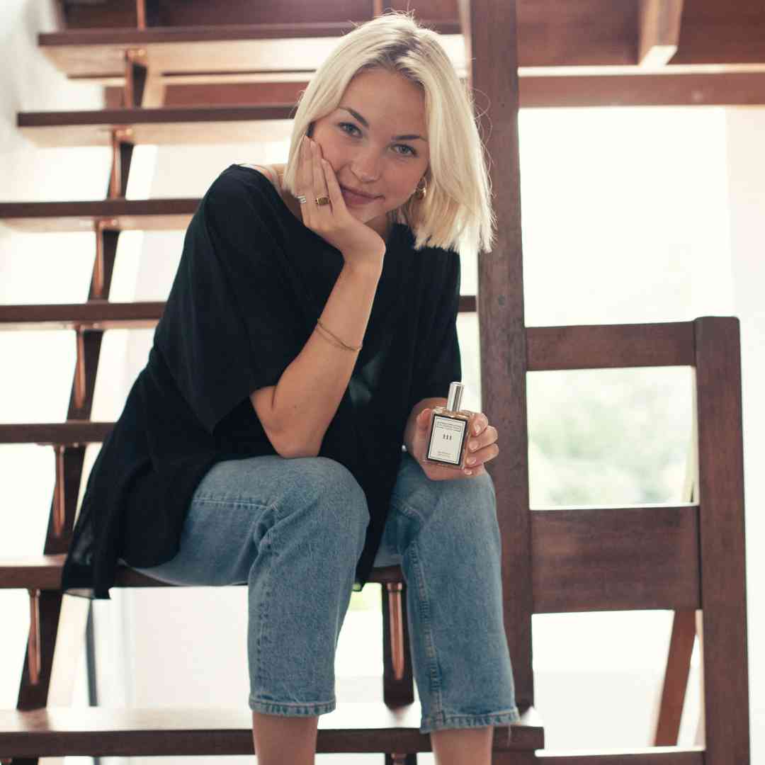 Image of a woman sat on some stairs holding a perfume bottle from The Essence Vault, is perfume a good gift for mother's day?