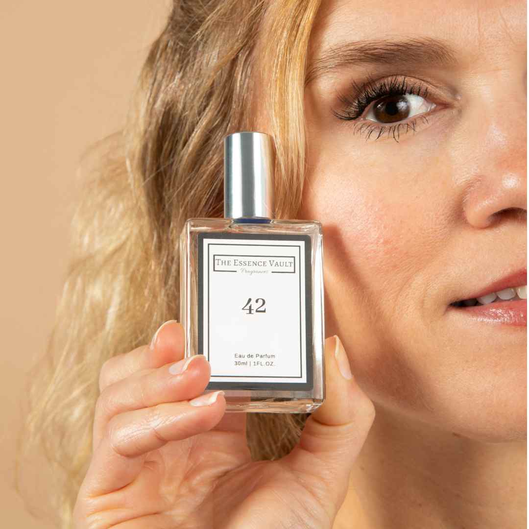 Image of a woman holding a perfume from The Essence Vault next to her face, from the blog The Perfect Mist: How To Make Perfume Last Longer